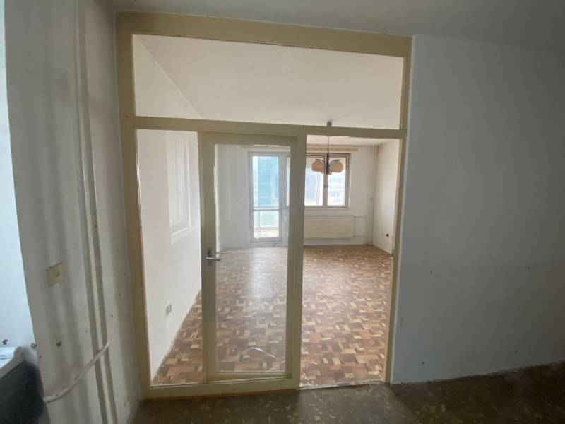 Interior of a 3-room apartment with parquet flooring and a large window.