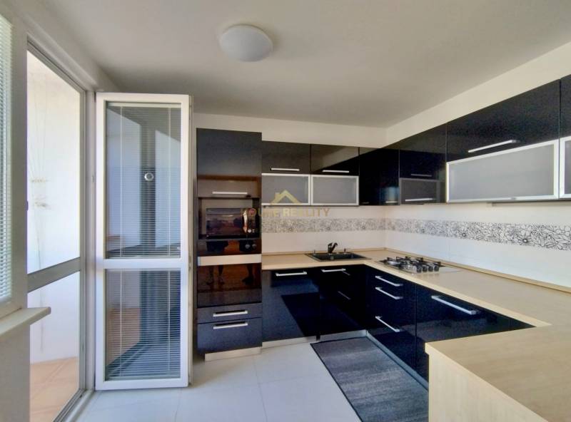 A kitchen with dark cabinets and built-in appliances in a three-room apartment.