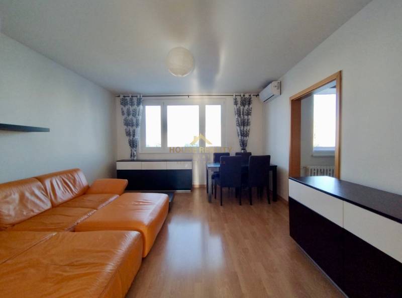 Living room in a three-room apartment with an orange sofa and a wooden decor floor.