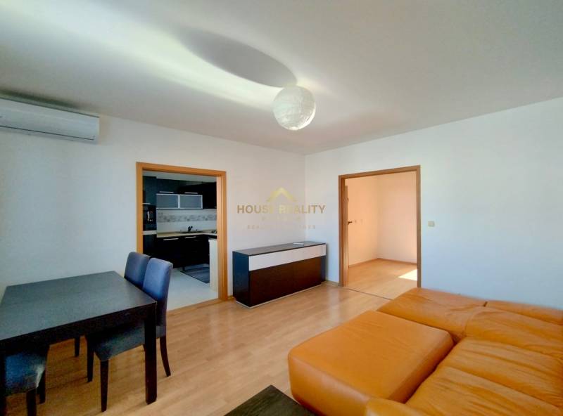 Living room in a three-room apartment with a wooden decor floor and a dining table.