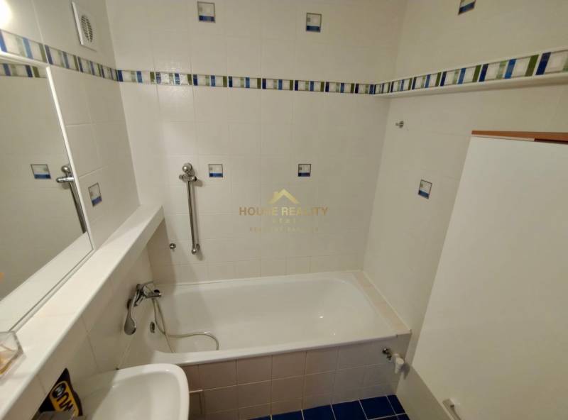 A bathroom with light tiles, a bathtub, and a sink in a 3-room apartment.