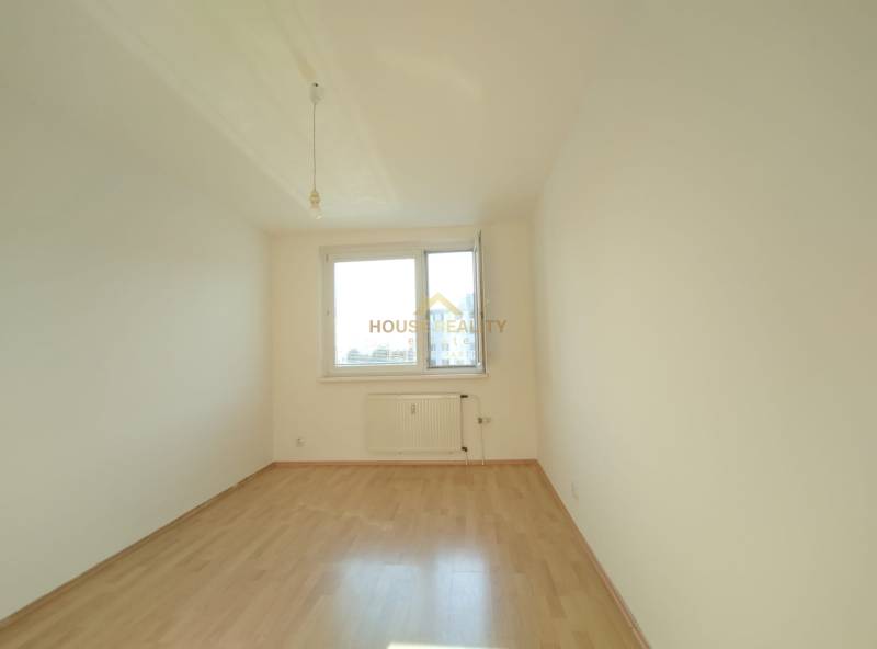 An empty room with a large window, white walls, and a wooden-patterned floor, 3-room apartment.
