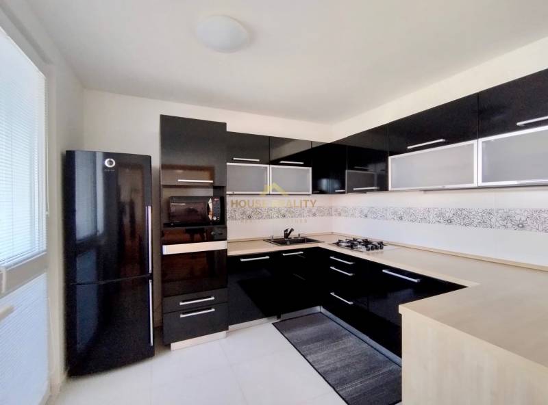 A kitchen in a 3-room apartment with black glossy cabinets and a corner stove.