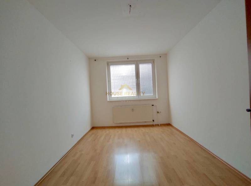 A room in a 3-room apartment with a wooden decor floor and white walls.