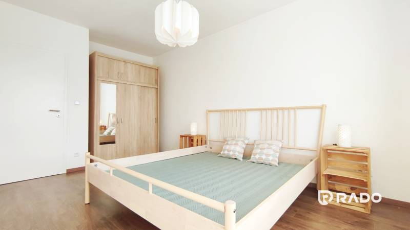 A bedroom with a wooden bed, built-in wardrobe, and nightstands in a two-room apartment.