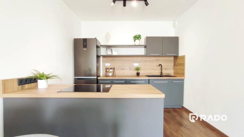 A kitchen in a 2-room apartment with a dark gray and wooden kitchen unit.