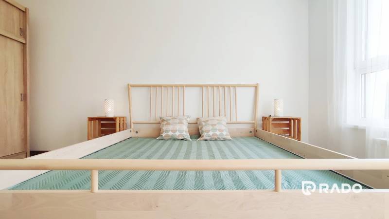 A bright bedroom with a wooden bed and pillows in a two-room apartment.