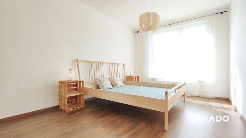 A bright bedroom with a wooden bed and nightstands in a two-room apartment.