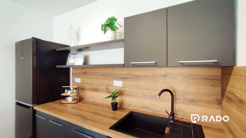 A kitchen in a 2-room apartment with gray cabinets and a wooden countertop.