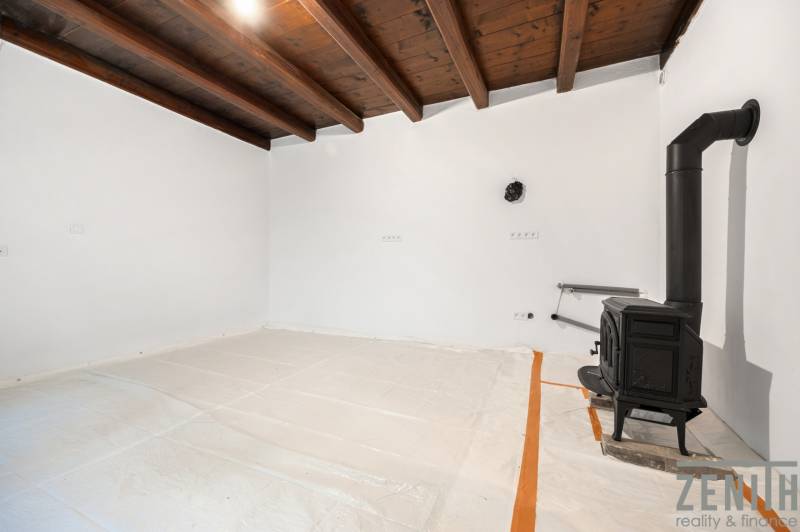 A white interior with a wooden ceiling and a stove in a family house.