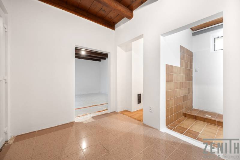 The interior of a family house with a wooden ceiling and adjoining rooms with tiles.