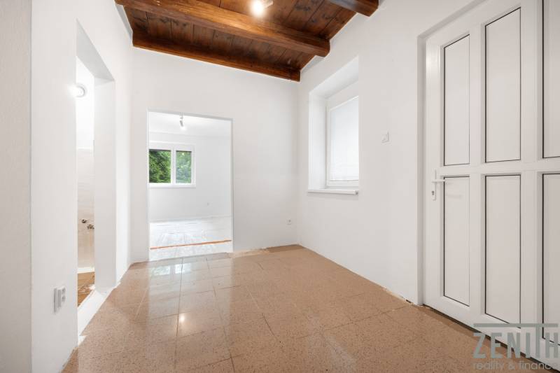 Interior of a family house with tiles, a wooden ceiling, and white walls.