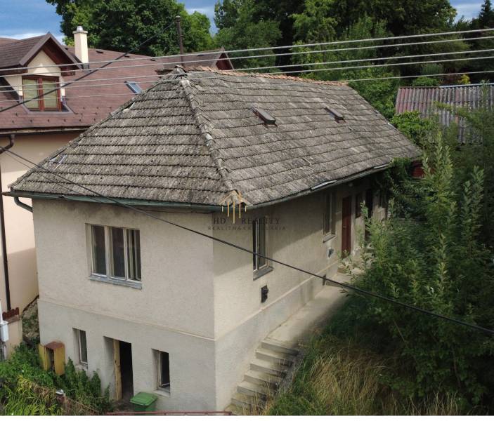 A family house under Bôd Bánoš in Banská Bystrica with a sloped roof and a garden.