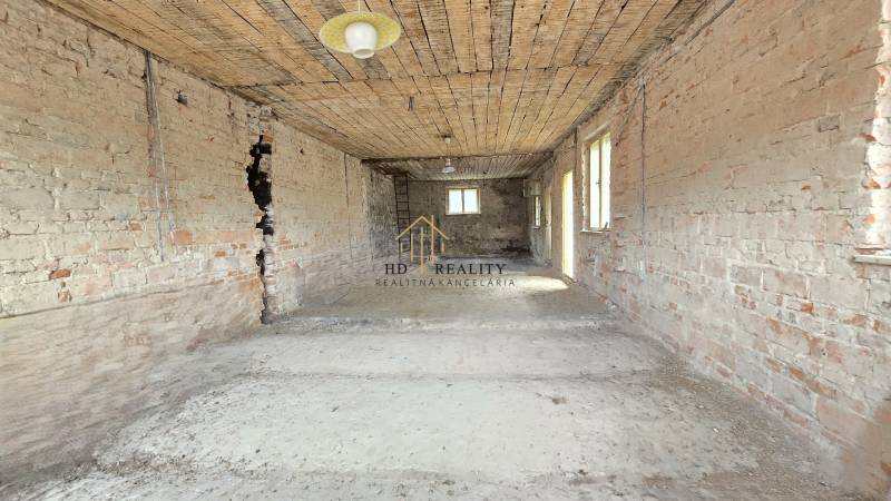 Unfinished interior of a family house with exposed brick walls and floor.