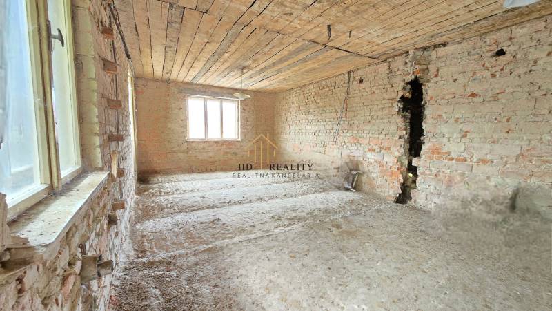 Unrenovated room with brick walls and a window in a family house.