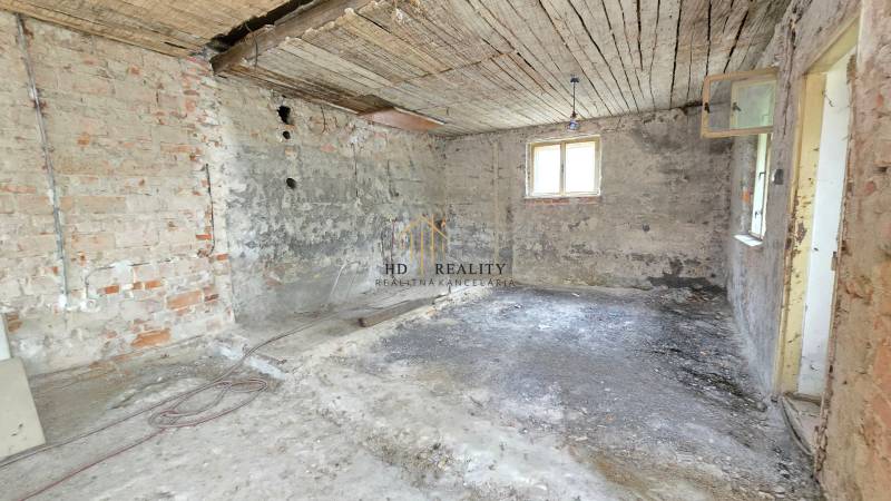 An inadequate interior of a family house with bare brick and plaster walls.