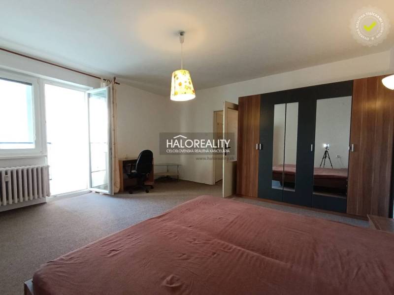 A spacious room in a one-room apartment with a bed, a wardrobe, and balcony doors.