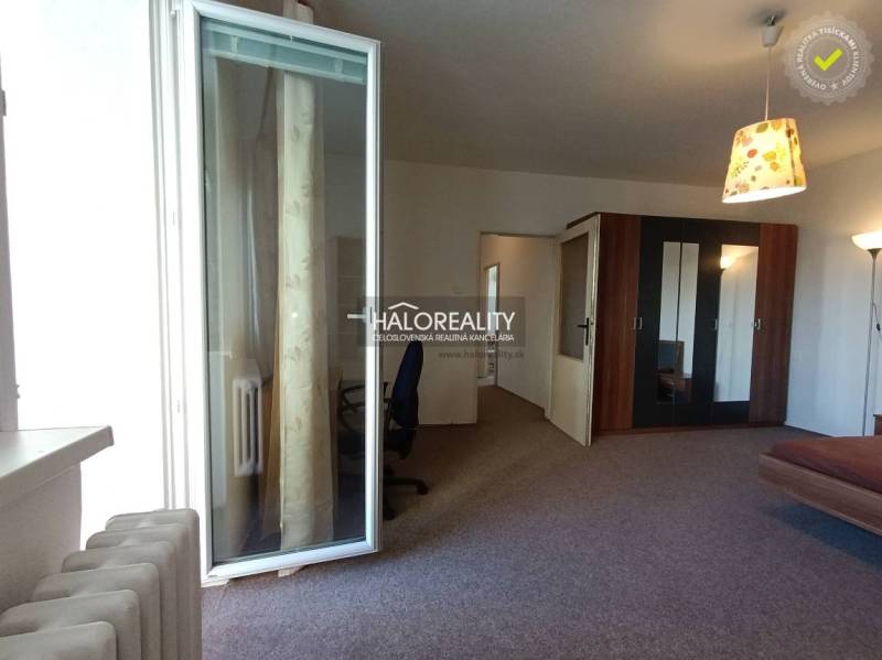 A room with slightly open balcony doors, a wardrobe, and an office chair.