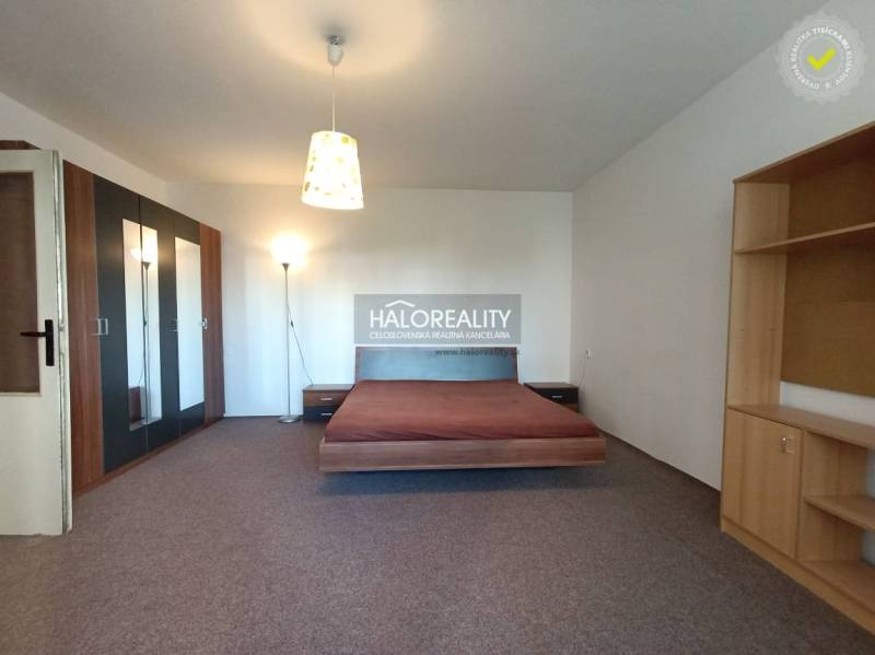 A stylish interior of a studio apartment with a bed, built-in wardrobe, and shelves.