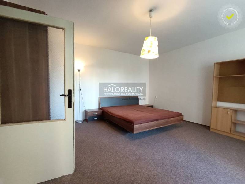 Bright bedroom in a studio apartment with a bed, lamp, and furniture.