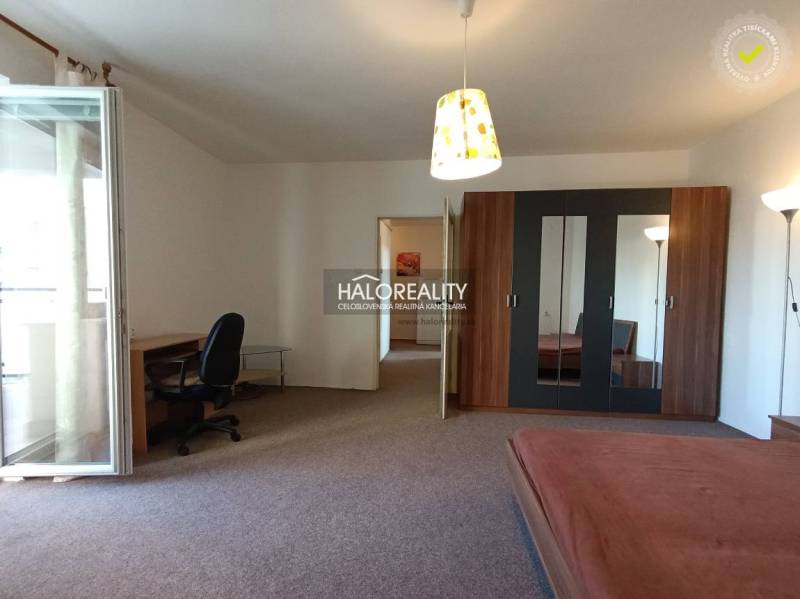 The interior contains a table, a chair, a wardrobe, and a bed in a studio apartment.