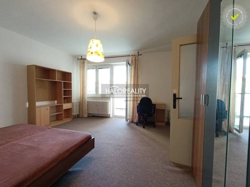 A bedroom in a one-room apartment with a built-in wardrobe and a desk.