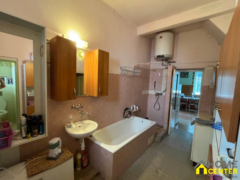 A bathroom in a family house with a shower, a bathtub, and wooden cabinets.