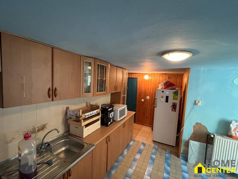 A kitchen in a family house with wooden cabinets, a microwave, and a refrigerator.