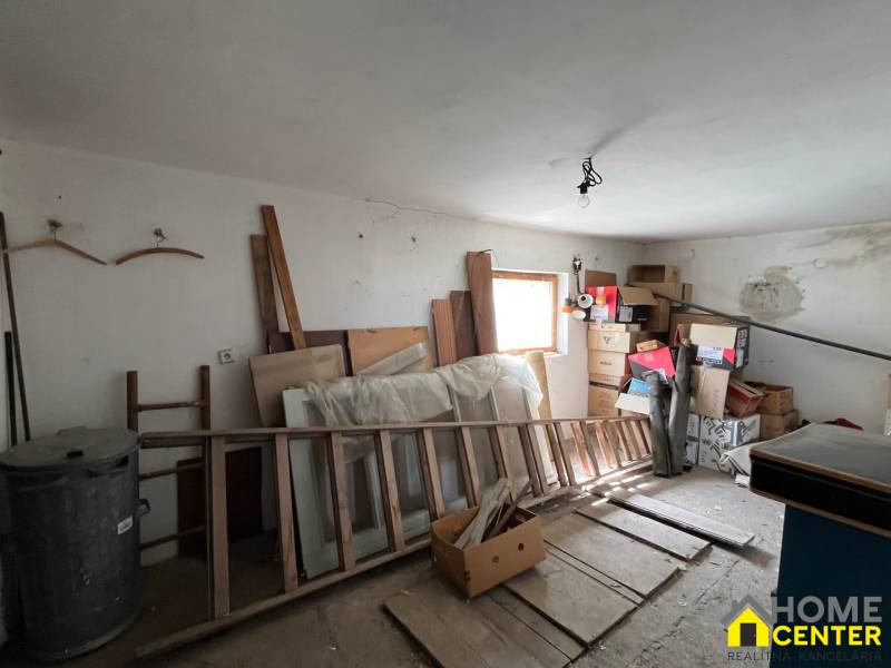 A mess in a room of a family house with stored cabinets, boxes, and wooden frames.