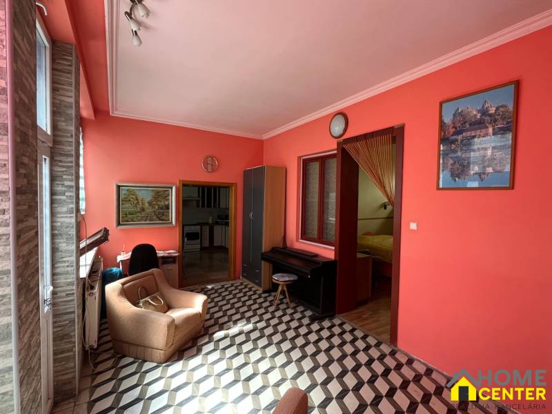 A living room in a family house with orange walls, an armchair, and checkered flooring.