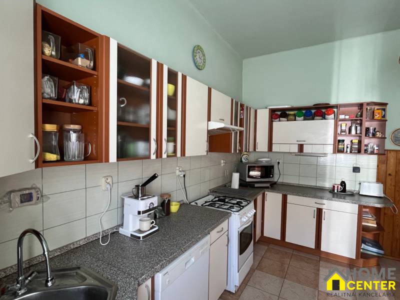 A kitchen in a family house with brown and white cabinets and a coffee maker.