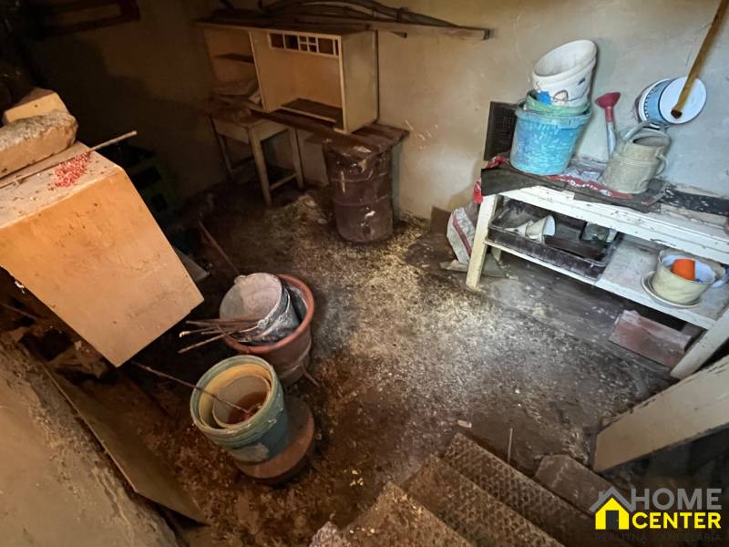 An old basement of a family house with a table, buckets, and tools in a dark room.