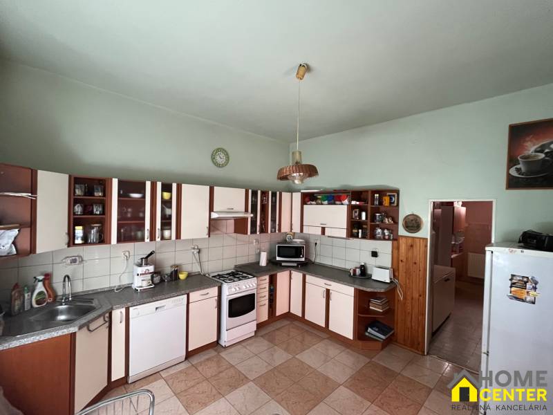 A kitchen in a family house with kitchen cabinets, appliances, and ceramic tiles.