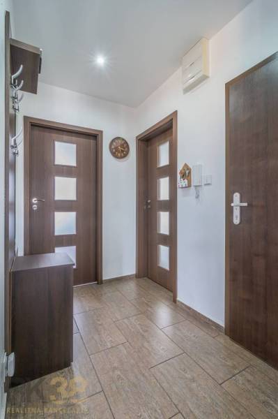 Hallway in a 3-room apartment, contains a door, a coat rack, and a clock.