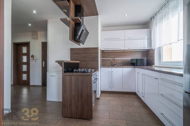 A kitchen in a 3-room apartment with white cabinets and wooden accessories.