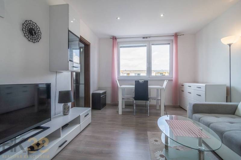 A bright living room with a table, television, and sofa in a three-room apartment.