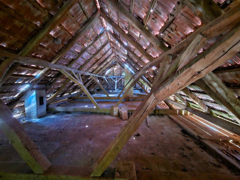 The attic of a family house with wooden beams and a preserved brick roofing system.