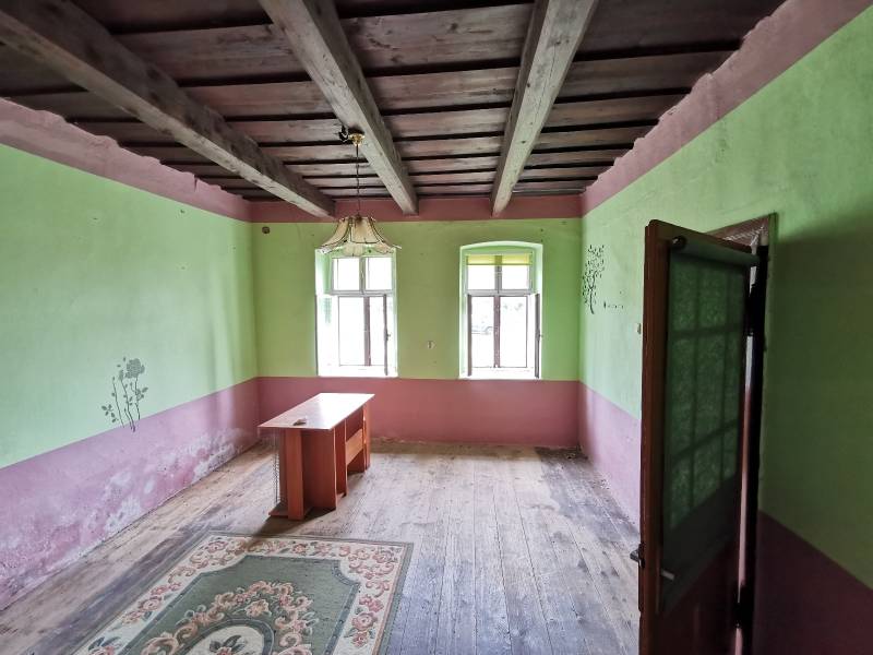 A room in a family house with a wooden ceiling, an old table, and a carpet.