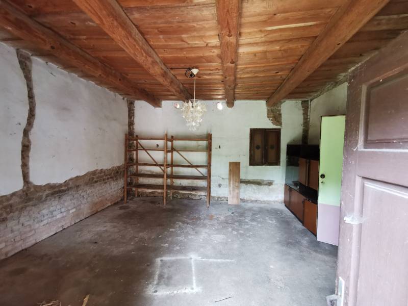 Interior of a family house with a wooden ceiling, simple shelf, and cabinet.