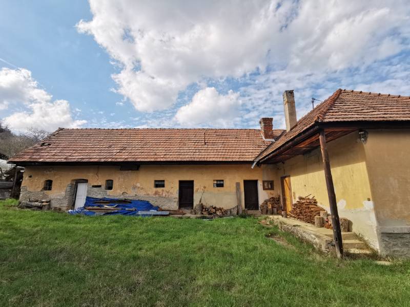 An older family house in Nitrianske Sučany surrounded by grass and wood on Nirtrianske Sučany street.