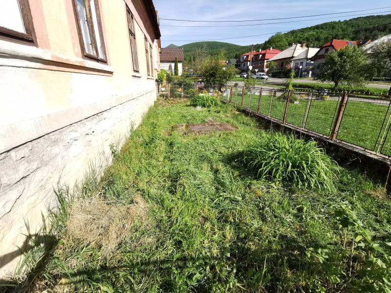 The garden of a family house in Nitrianske Sučany with a view of the street and hills.