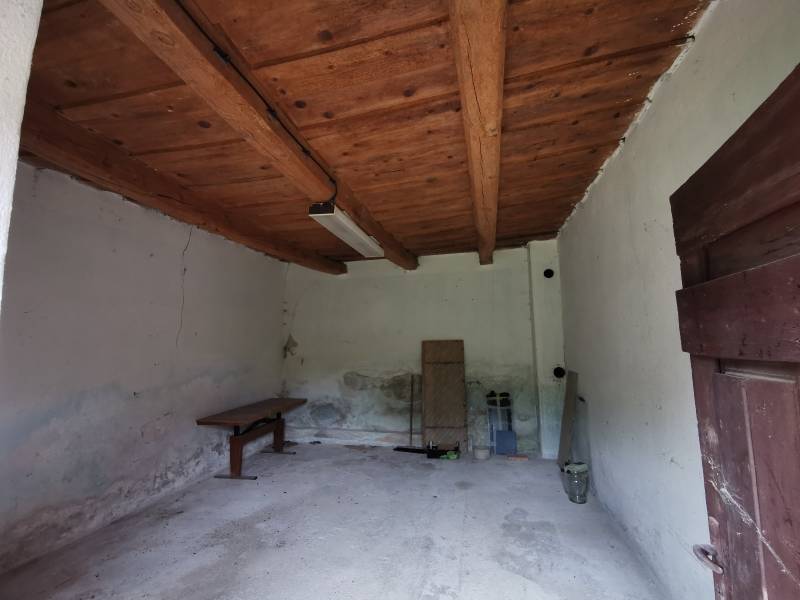 A wooden ceiling in a room of a family house with simple furnishings and white walls.