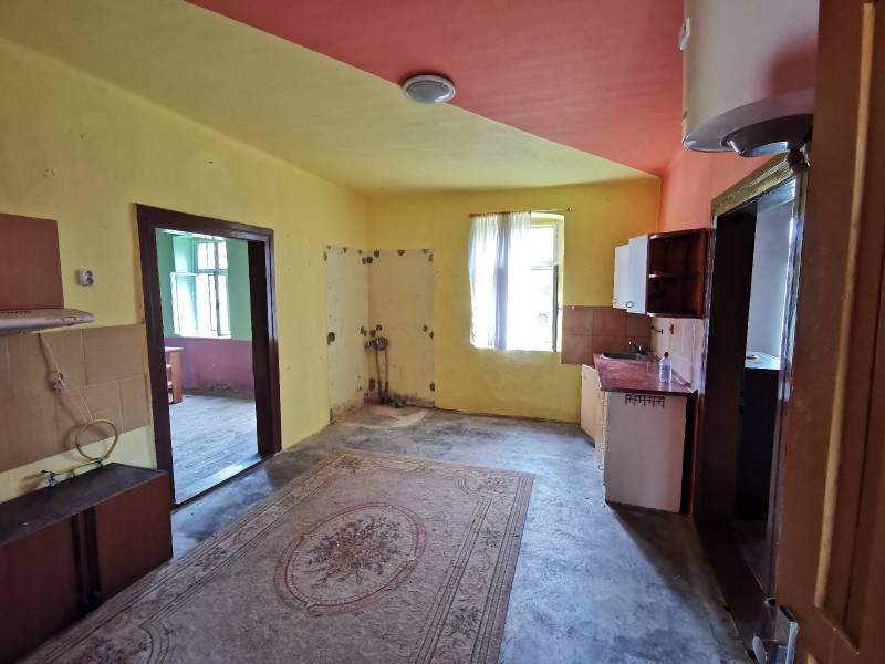 Interior of a family house with a kitchen unit and a door opening onto variously colored walls.