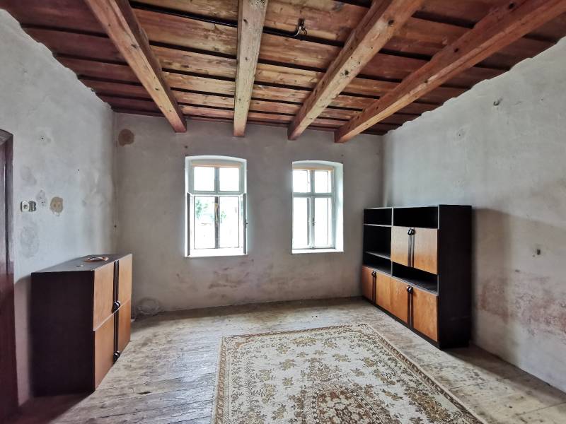 A room in a family house with a wooden ceiling, windows, cabinets, carpet on the floor.