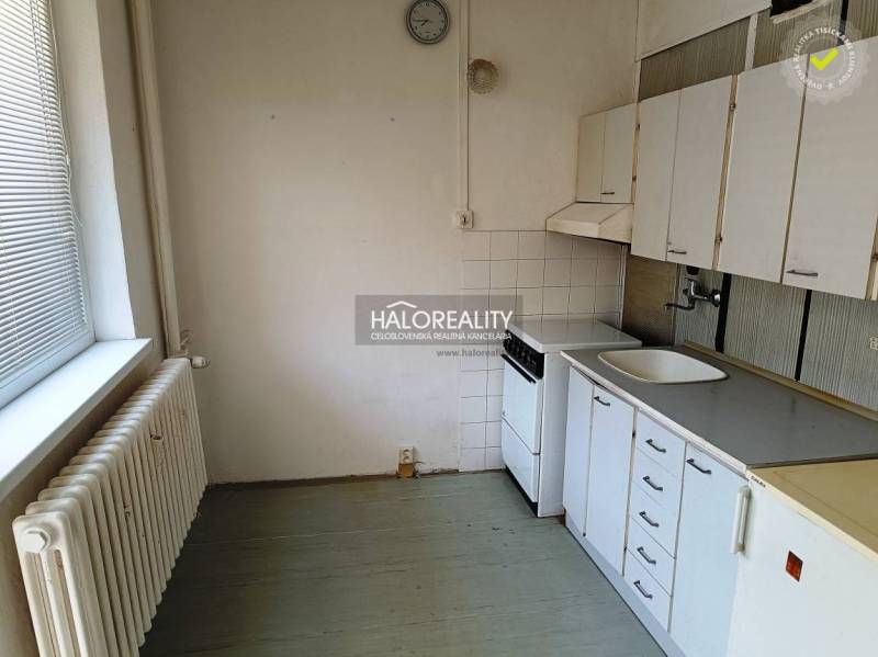 A kitchen in a studio apartment with a stove, sink, and kitchen cabinets.
