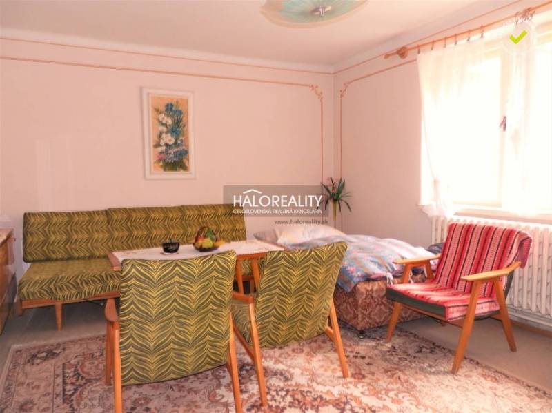 Living room in a family house, vintage furniture, carpet, light walls, large window.