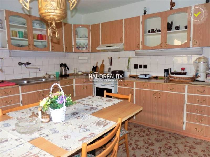 A kitchen in a family house with a wooden cabinet, a dining table, and floral decoration.