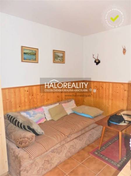 Interior of a family house with a sofa, paintings on the wall, and wooden paneling.