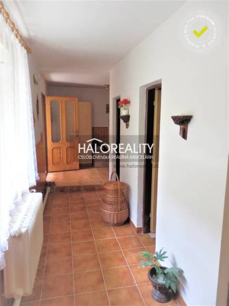 A hallway of a family house with tiles, room doors, and a basket on the floor.