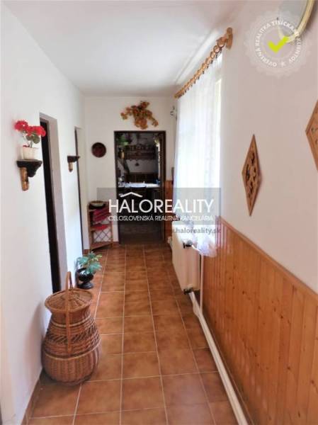 A hallway in a family house with wooden paneling, floral decoration, and a wicker basket.